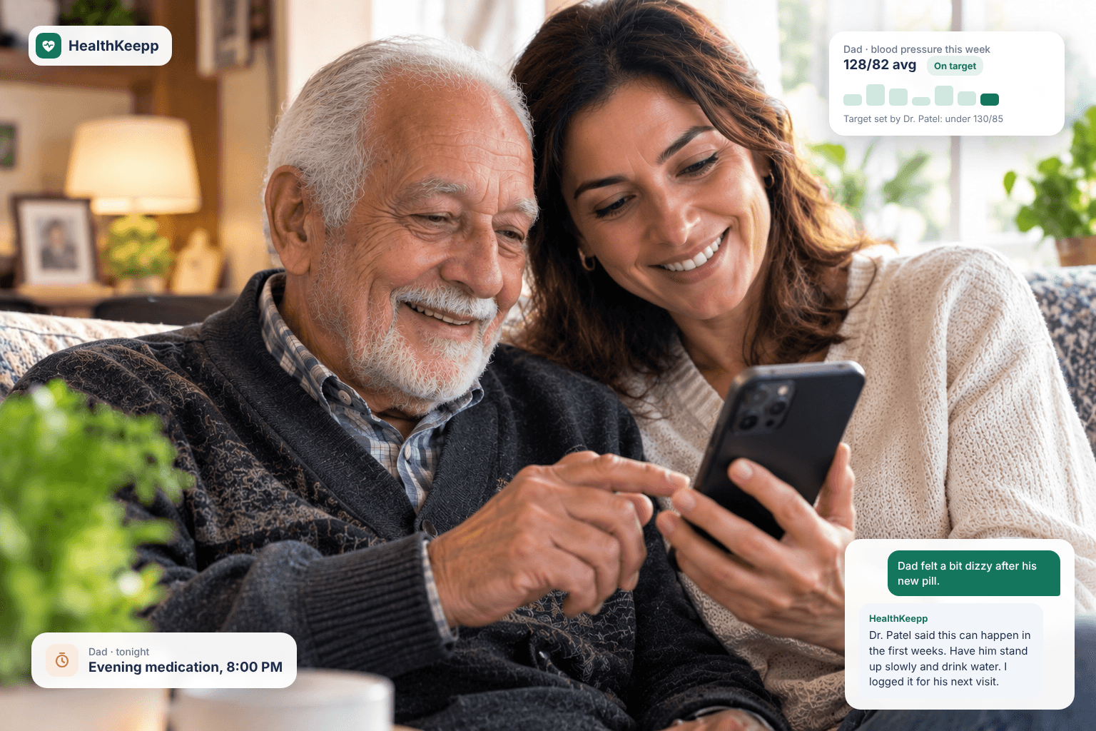 A smiling daughter and her elderly father looking at HealthKeepp on a phone. App cards show Dad's blood pressure averaging 128/82, on target for the goal set by his doctor, an evening medication reminder, and a reply explaining that his doctor said dizziness can happen in the first weeks of his new pill.